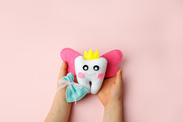 Little child holding felt tooth fairy toy in his hands on pink background. Easy and funny kids...