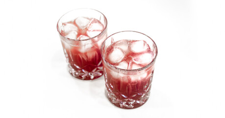 Bourbon Cherry Sour in clear crystal glass served chilled, on the rocks. White Isolated background.