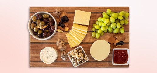 Delicious Cheese Assortment on a wooden board with fruit, nuts, jelly, and olives. Gourmet Charcuterie Arrangment.