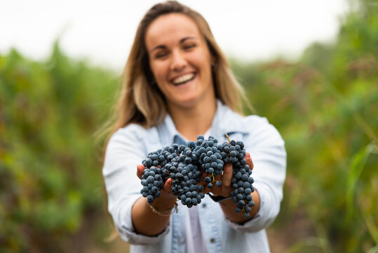 smiling woman holding grape bunches