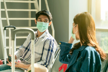 Asian man traveler sitting on the seat keep spaced for social distancing waiting in an airport terminal. concept of new normal travel