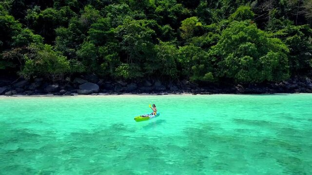 Cute Asian Girl on a Kayak at Monkey Beach, Phi Phi Island, Thailand. Drone.