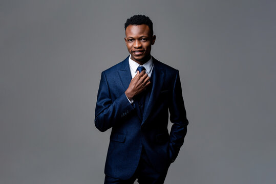 Portrait of young smiling happy handsome African man wearing formal business suit in isolated studio gray background