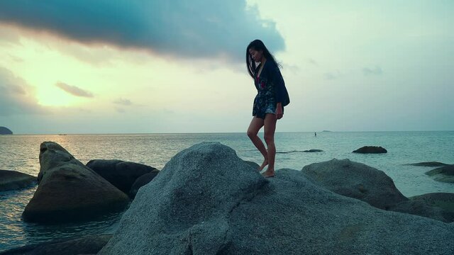 Cute Asian Girl Walking on a Rock at Beautiful Sunset in Slow Motion, Thailand.