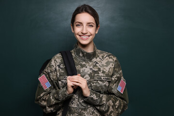 Female cadet with backpack near chalkboard. Military education