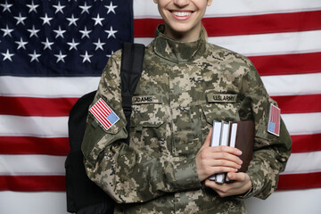Female cadet with backpack and books against American flag, closeup. Military education