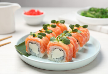 Tasty sushi rolls with salmon served on white table