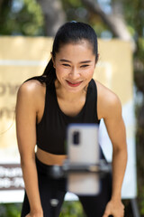 Asian sporty girls dancing with their smartphones at the park. - obrazy, fototapety, plakaty
