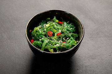 Wakame seaweed with sesame and chilli on gray background. Asian food concept.