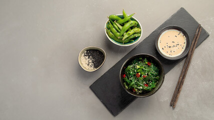 Wakame seaweed with sesame and chilli on gray background. Asian food concept.