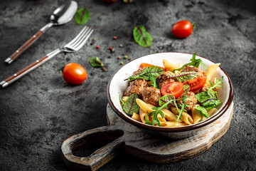 Italian pasta. penne pasta with meatballs in tomato sauce in a white craft bowl on a grey stone background. banner, menu recipe place for text, top view