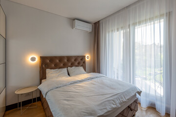 Fototapeta na wymiar Bedroom interior with large windows and curtains