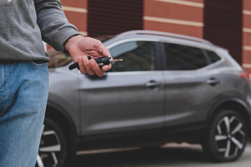 Man in front of the new car and holding keys. Salesman is carrying the car keys delivered to the...