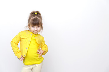 happy little girl in yellow clothes posing against gray wall background, copy space