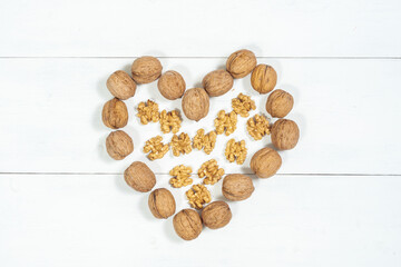 heart of whole walnuts and kernels on a light wooden background. Healthy food nuts.