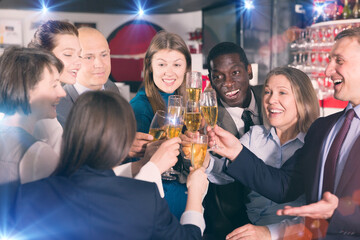 Glad males and females clinking glasses on corporate party