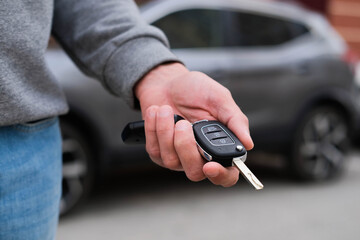 Man in front of the new car and holding keys. Salesman is carrying the car keys delivered to the...