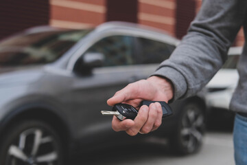 Man in front of the new car and holding keys. Salesman is carrying the car keys delivered to the customer at the showroom with a low interest offer.  Rent, credit, insurance, car purchase. Copy space - obrazy, fototapety, plakaty