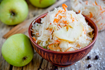 Homemade sauerkraut with green apple and carrot in a clay bowl - obrazy, fototapety, plakaty