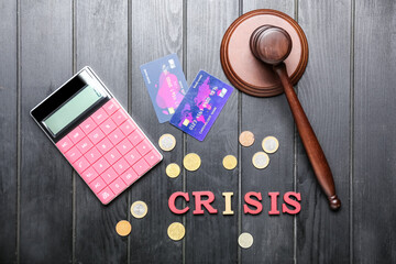 Judge gavel with calculator, credit cards, coins word CRISIS on dark wooden background