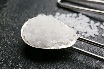 Spoon with salt on dark background