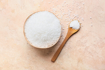 Bowl and spoon with salt on color background
