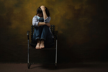 Naklejka na ściany i meble Woman wearing face mask depression scratching her head while sitting on the chair.Depression associated with COVID-19