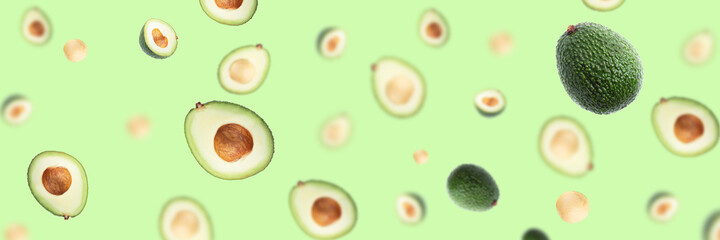 Creative pattern with flying avocado halves on green background.