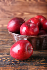 Basket with fresh red apples on wooden background
