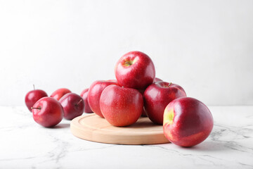 Board with fresh red apples on white background