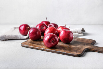 Board with fresh red apples on light background
