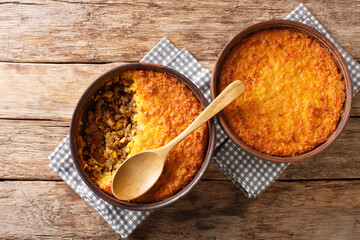 Pastel de choclo corn pie is a Chilean dish based on sweetcorn and beef closeup in the pots on the table. Horizontal top view from above