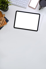 White office desk with digital tablet, mobile phone, coffee cup and houseplant on white table. Top view with copy space, flat lay.