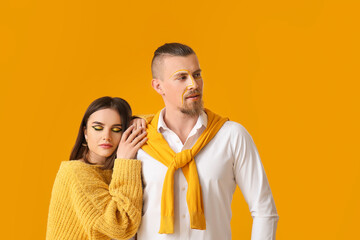 Stylish young couple on yellow background