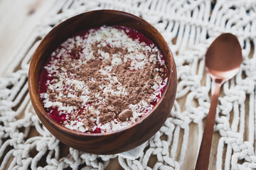 vegan smoothie bowl with raspberry vanilla oat milk smoothie topped with cocoa and coconut flakes,...