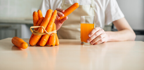 carrots and carrot juice in a glass beaker in the kitchen. Young guy and healthy food