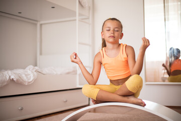 Little girl doing yoga exercise at home on board.