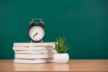 Alarm clock on stack of book  on blackboard background,back to school concept