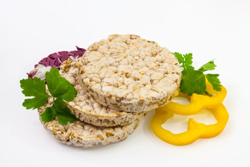 Round crispy popcorn and rice bread with yellow bell pepper rings and spicy herbs. Isolated on a white background.