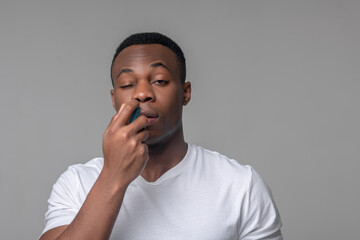 Unhappy dark skinned man with spray near nose