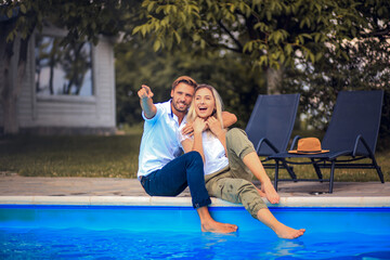  Happy smiling couple sitting by the pool.