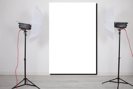 mockup empty room with blank white screen poster studio lights on tripod stands in Concept background with modern lighting equipment for professional photographer