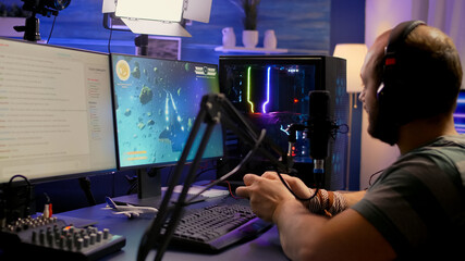Streamer man winning space shooter video game during esport tournament. Pro gamer using wireless...