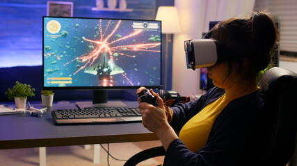 Pro cyber gamer losing online video game tournament wearing virtual reality headset. Professional player using controller for space shooter championship sitting on gamining chair late at night © DC Studio
