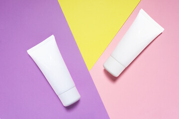 Creative beauty fashion concept photo of cosmetic recyclable bottle lotion cream on purple yellow pink background.