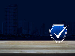 Fototapeta na wymiar Security shield with check mark flat icon on wooden table over modern office city tower and skyscraper, Technology internet cyber security and anti virus concept