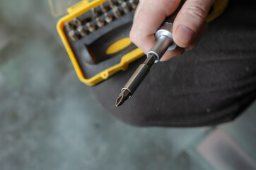 Defocus, selective focus, blur. Man collects screwdriver from yellow and black box with screwdriver bits.