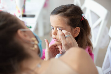 Time for make up.  Mother helping her little girl with make up.