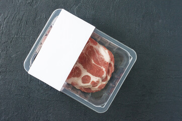 Raw marbled pork steak in vacuum packaging on black background, top view, logo mockup for design