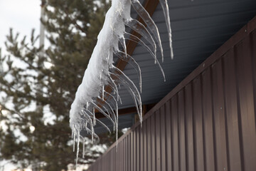 Icicle hanging off of a house. Winter landscape. Icicles hanging off roof rain gutter.